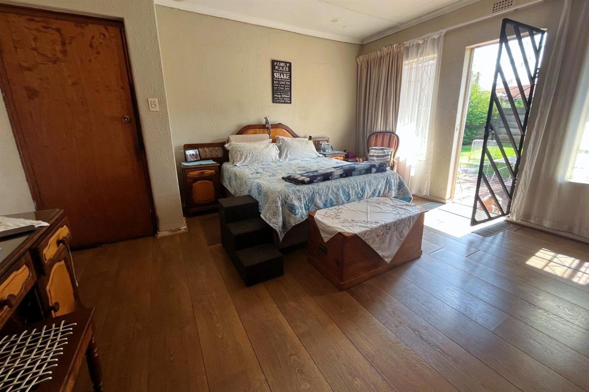 A bedroom featuring laminate flooring and direct access to the garden through a sliding door with a security gate.