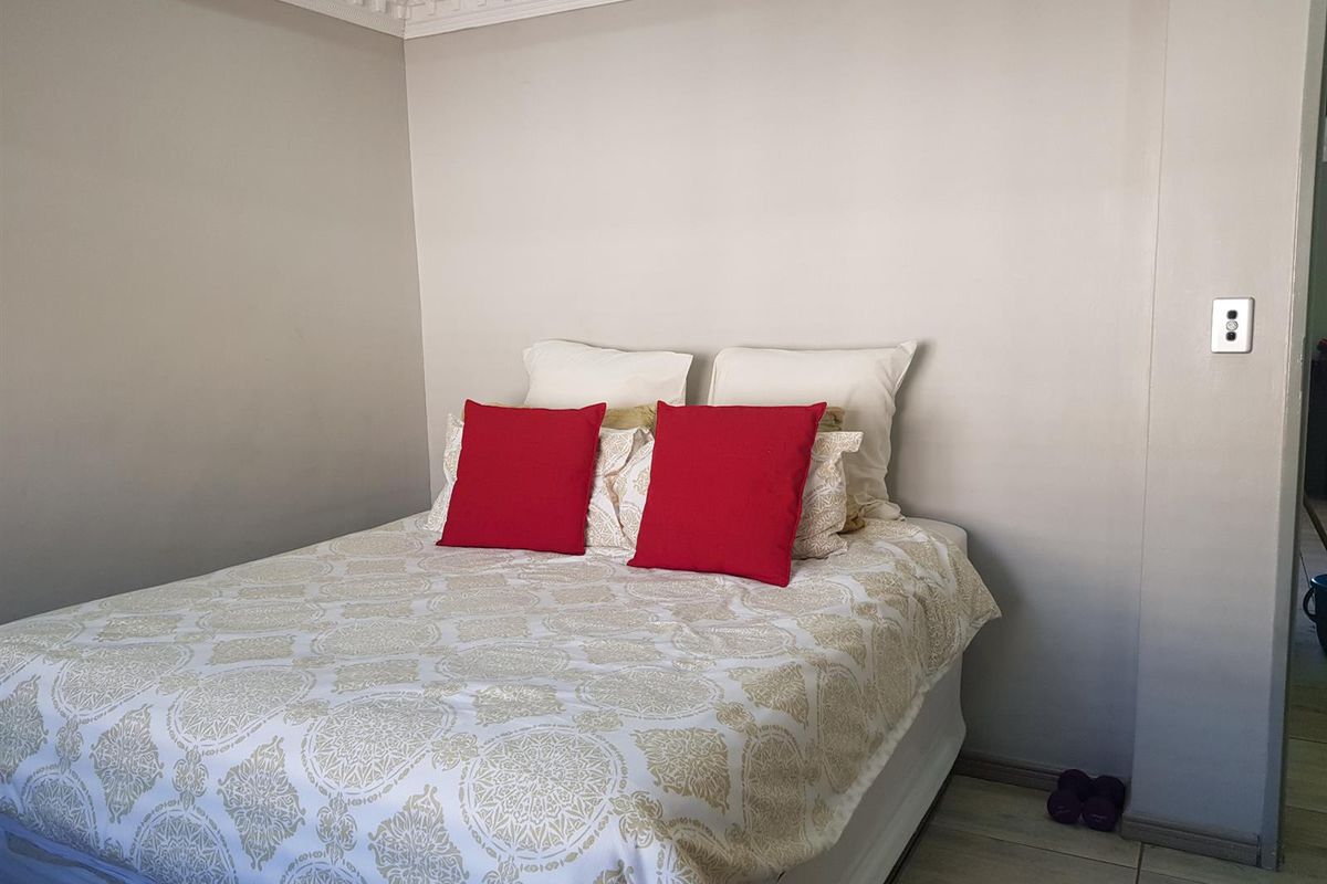 A bedroom featuring tiled flooring and decorative ceiling cornicing, providing a neutral foundation for interior design.
