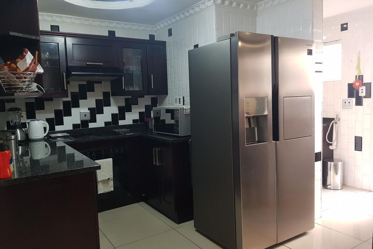 A kitchen featuring dark wood cabinetry, granite countertops, a built-in oven, and a distinctive black and white tiled backsplash with decorative ceiling molding.