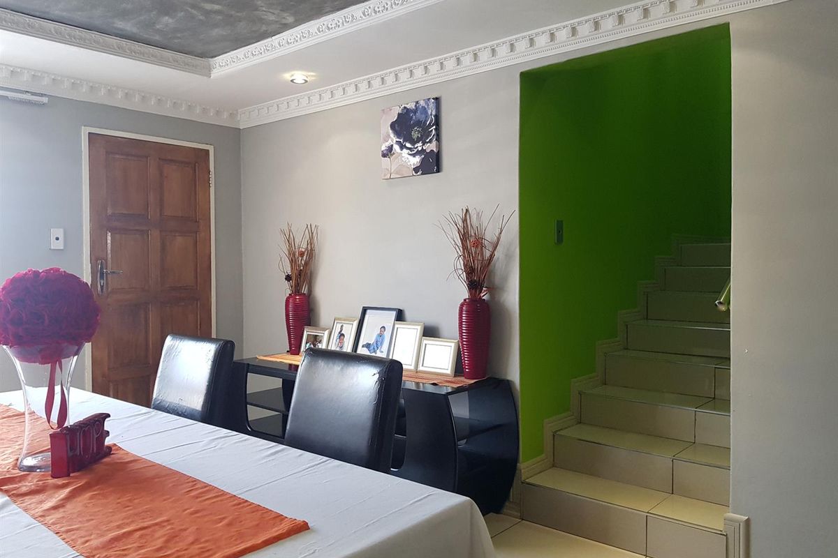 Living area featuring decorative ceiling cornicing, recessed lighting, and a tiled staircase leading to the upper level.