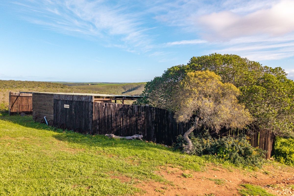 An aerial view of a rustic timber-clad farm structure situated in a rural landscape, featuring a simple shed-style design.