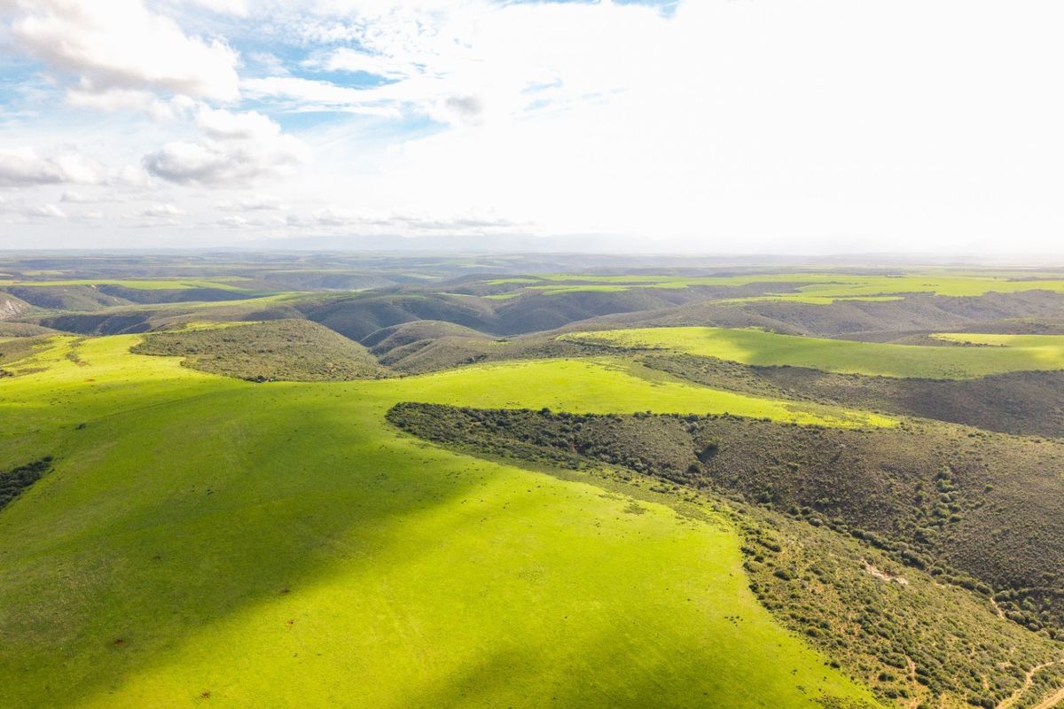 An expansive aerial view of the rolling green hills and natural landscape of the farm property.