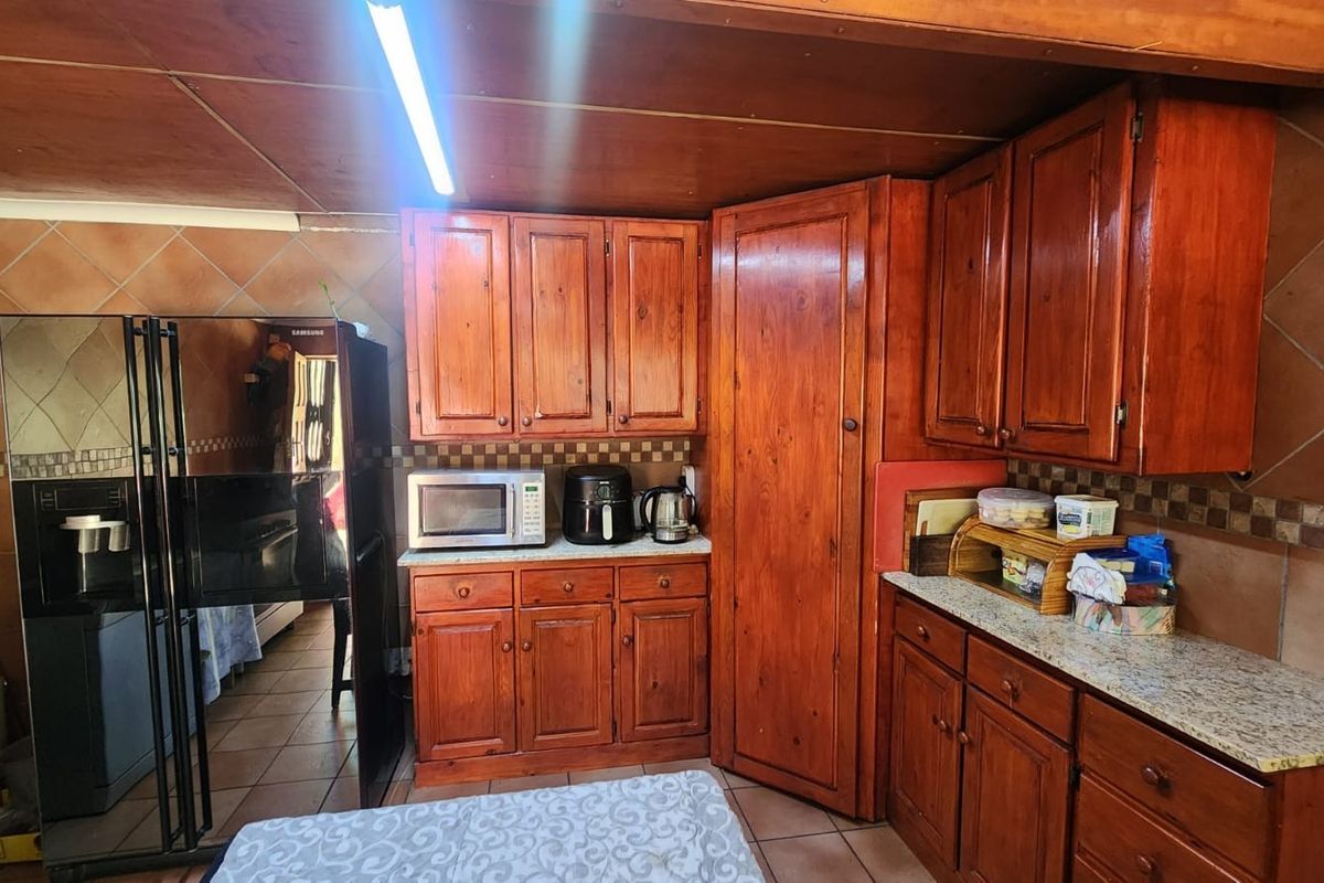 A functional kitchen featuring traditional wooden cabinetry, granite countertops, and tiled finishes, offering a classic aesthetic with potential for modern updates.