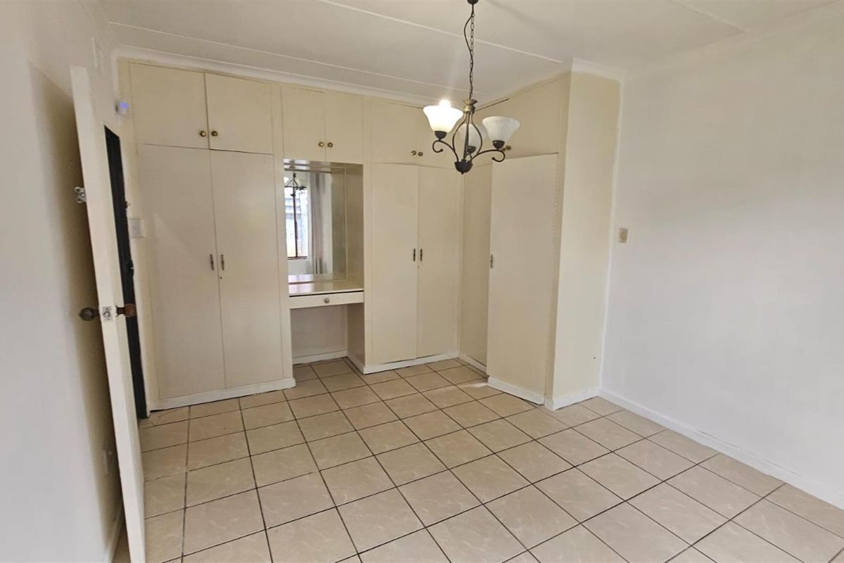 A bedroom featuring built-in cupboards with an integrated vanity area and tiled flooring.