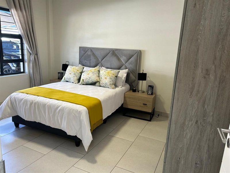 A well-maintained bedroom featuring neutral tiled flooring and a built-in cupboard, offering a clean and functional living space.
