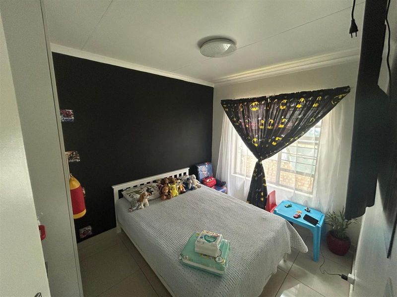 A functional bedroom featuring tiled flooring, a built-in wardrobe, and a feature wall, providing a comfortable space for a child or guest.
