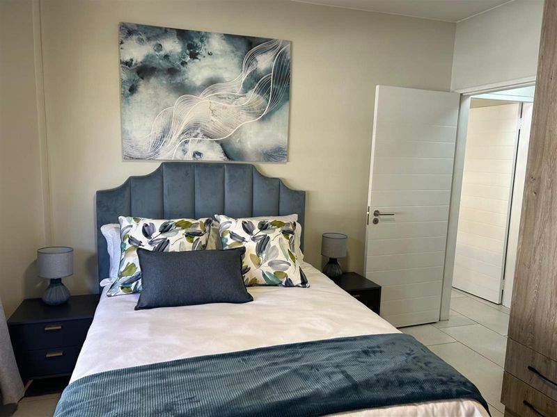 A well-maintained bedroom featuring tiled flooring, a built-in wardrobe, and a neutral color palette.