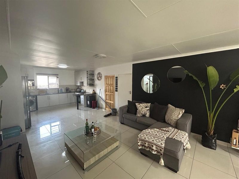 Open-plan living area featuring a modern kitchen with built-in cabinetry and tiled flooring throughout, creating a seamless flow between the kitchen and lounge space.