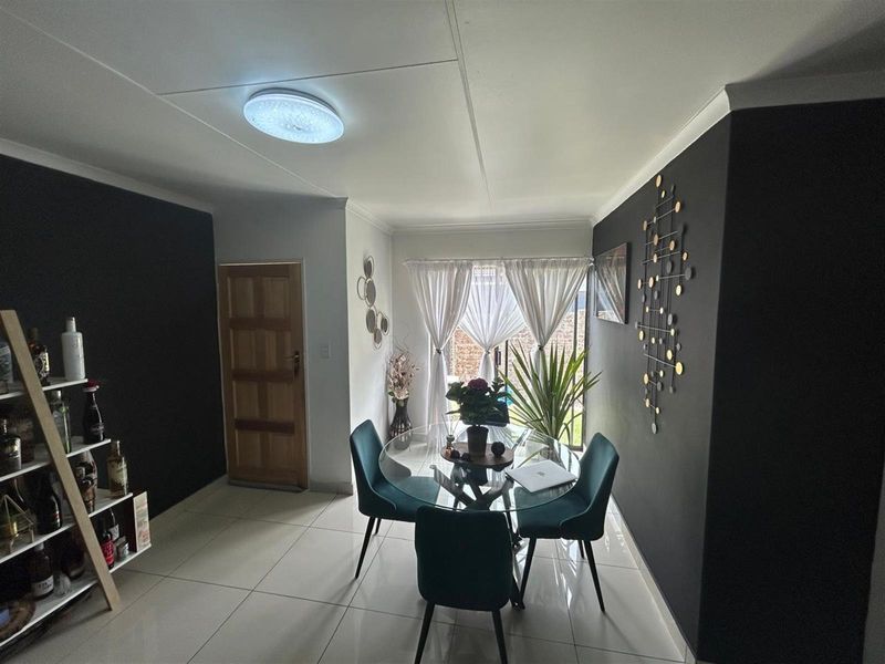A well-maintained dining area featuring tiled flooring, coved cornicing, and a sliding glass door providing natural light.