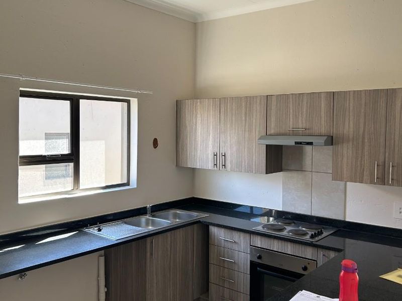 A functional kitchen featuring wood-look laminate cabinetry, granite countertops, built-in oven, electric hob, and tiled flooring, offering a clean and practical workspace.