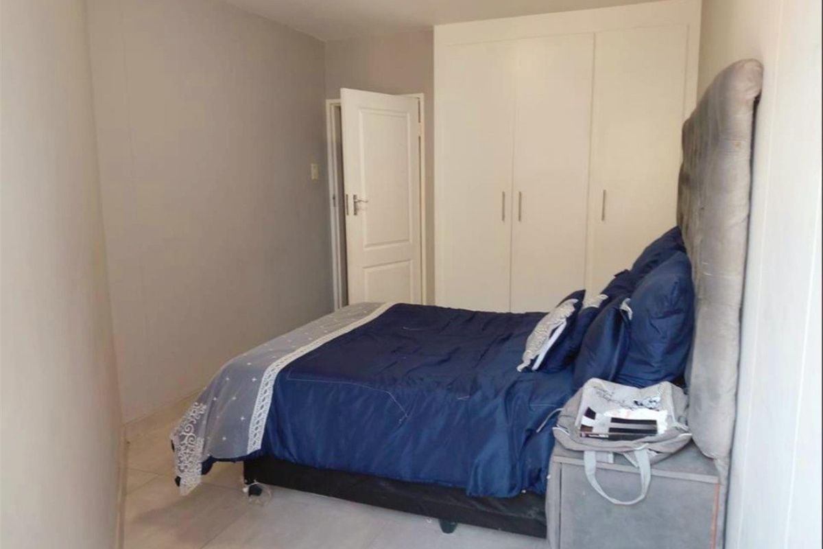 A bedroom featuring built-in cupboards and tiled flooring, providing a functional and neutral living space.