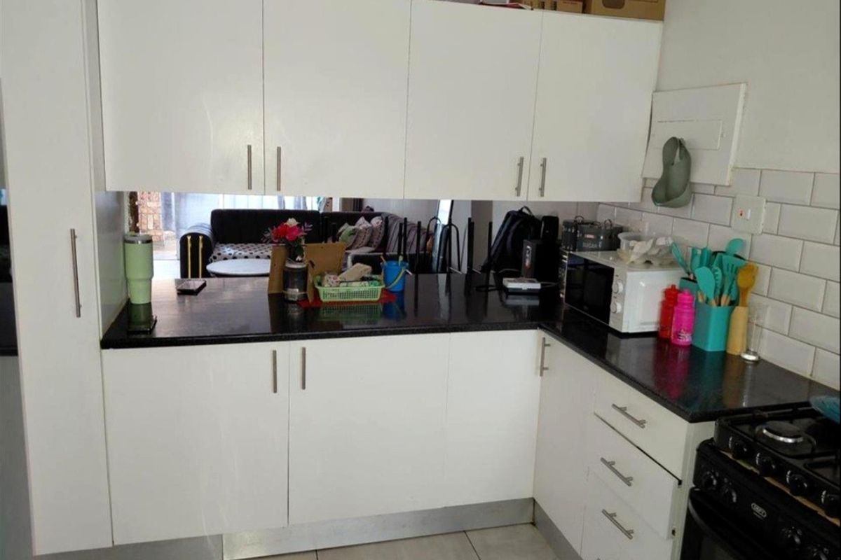 A functional kitchen featuring white cabinetry, dark granite countertops, and a classic subway tile backsplash, providing a clean and practical workspace.