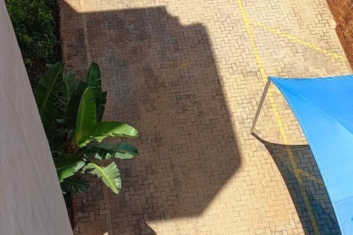 Aerial view of the apartment complex parking area featuring paved surfaces, a built-in brick braai facility, and a shaded parking bay.