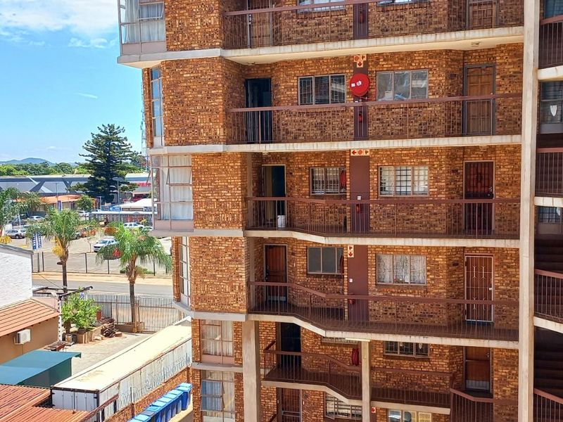 Exterior view of a multi-story apartment building featuring face-brick facade, open-air walkways, and metal security railings.