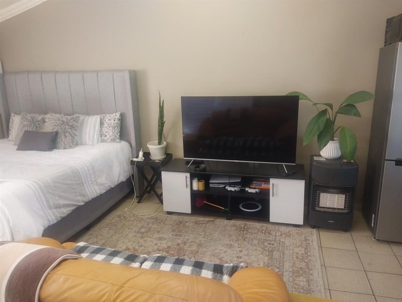 A bedroom featuring tiled flooring and neutral wall finishes, providing a functional space with room for a bed and entertainment setup.