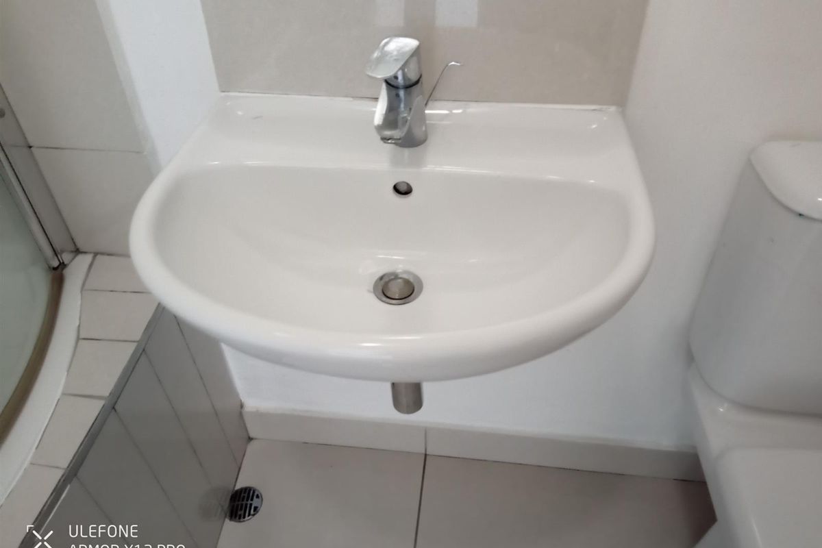 A compact bathroom featuring a wall-mounted ceramic basin with a chrome mixer tap and a tiled floor.