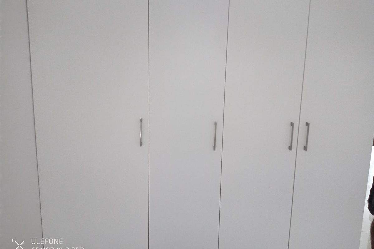 A set of white built-in bedroom cupboards with modern silver handles, providing ample storage space.