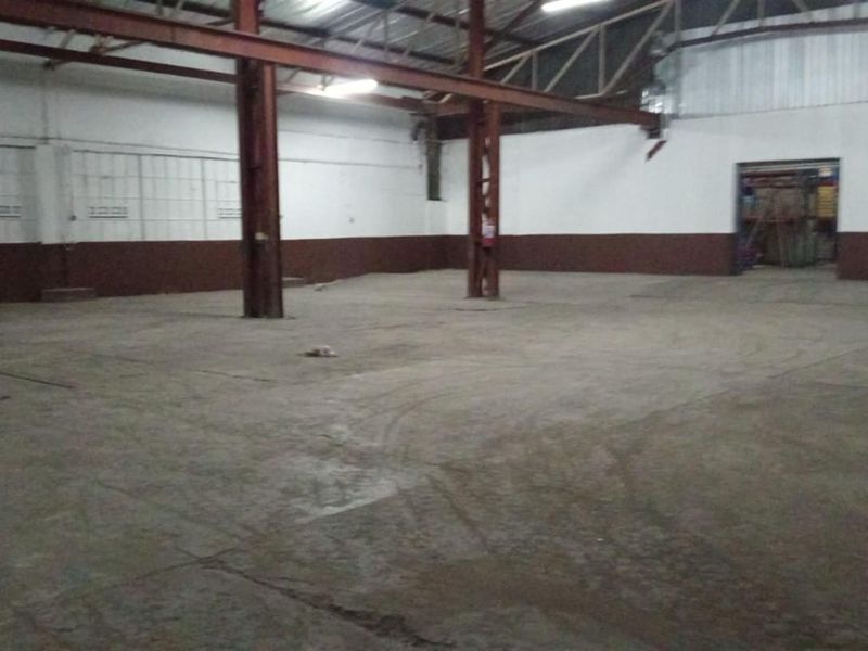 Spacious industrial utility area featuring exposed steel structural beams, concrete flooring, and high ceilings, suitable for warehouse or workshop use.