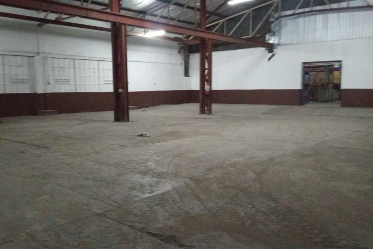 Spacious industrial utility area featuring exposed steel structural beams, concrete flooring, and high ceilings, suitable for warehouse or workshop use.