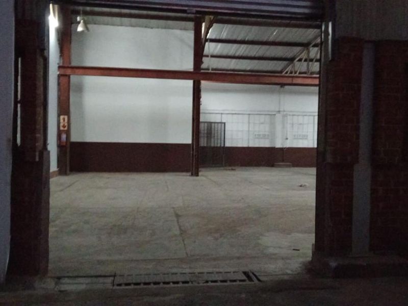 Spacious commercial utility or warehouse area featuring exposed steel structural beams, concrete flooring, and high ceilings, suitable for industrial or storage use.