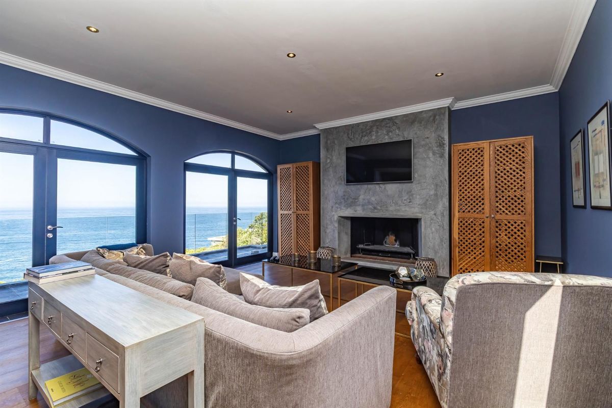 Spacious living room featuring a prominent fireplace, hardwood flooring, and large arched doors offering expansive ocean views.