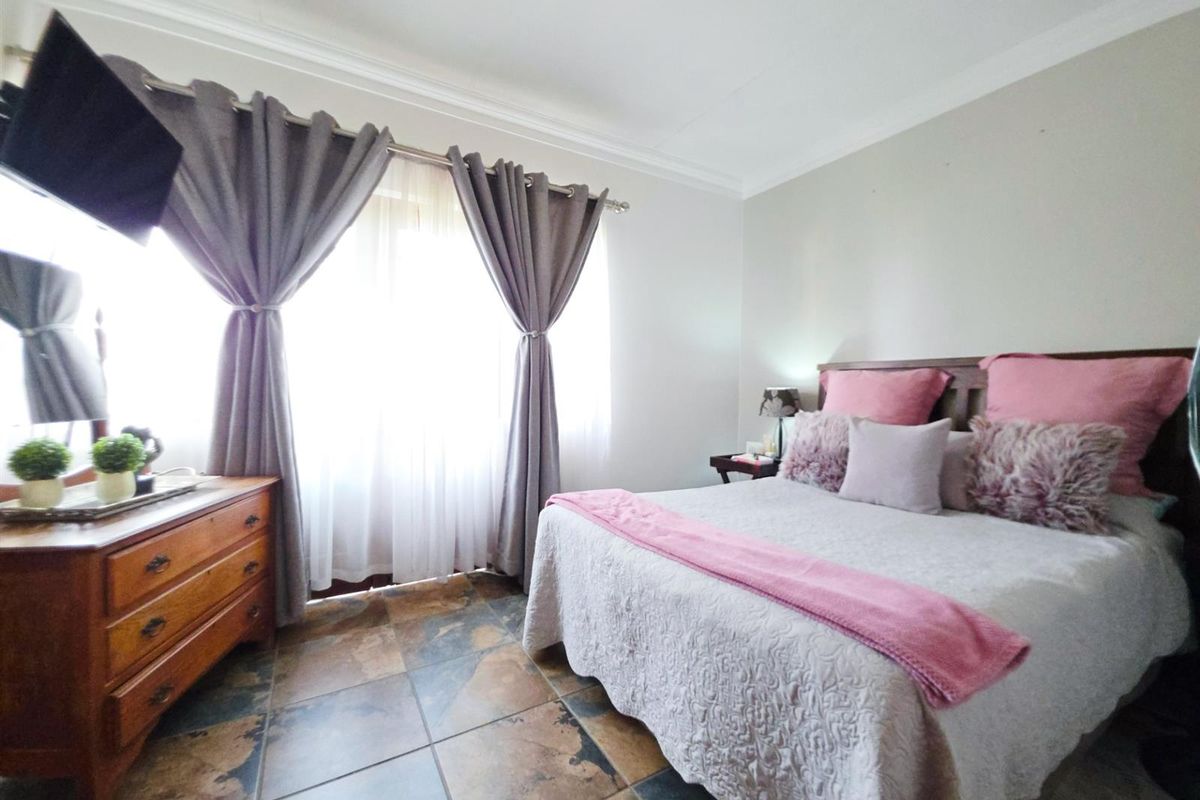 A well-lit bedroom featuring tiled flooring and coved ceiling details, providing a comfortable and functional sleeping space.