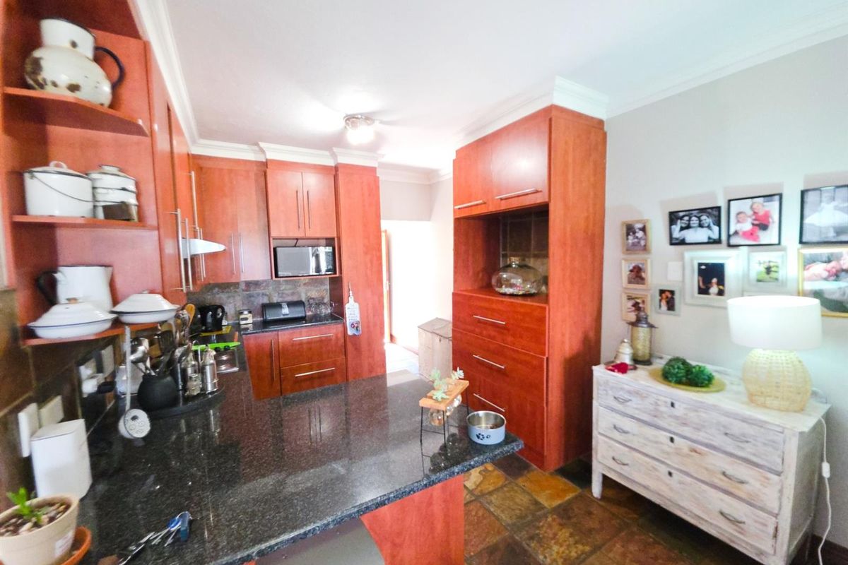 A functional kitchen featuring warm-toned wooden cabinetry, dark granite countertops, and durable stone tile flooring, offering ample storage and workspace.