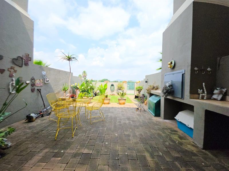 A paved outdoor patio area featuring a built-in braai and enclosed by boundary walls, offering a functional space for outdoor entertaining.