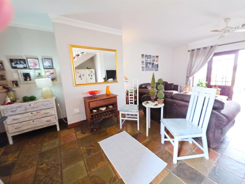 A living room area featuring natural slate tile flooring, crown molding, and a ceiling fan, with access to an outdoor space via sliding glass doors.