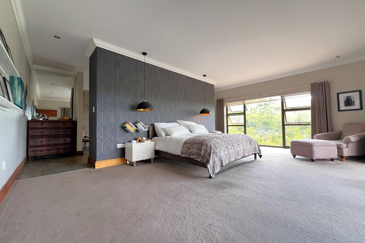 Spacious bedroom featuring a feature wall, plush carpeting, and large windows offering natural light and scenic views.