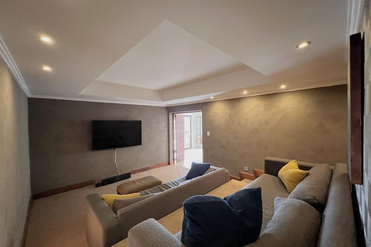 A comfortable living room featuring a recessed ceiling with integrated downlighting and neutral wall finishes, providing a cozy atmosphere for relaxation.