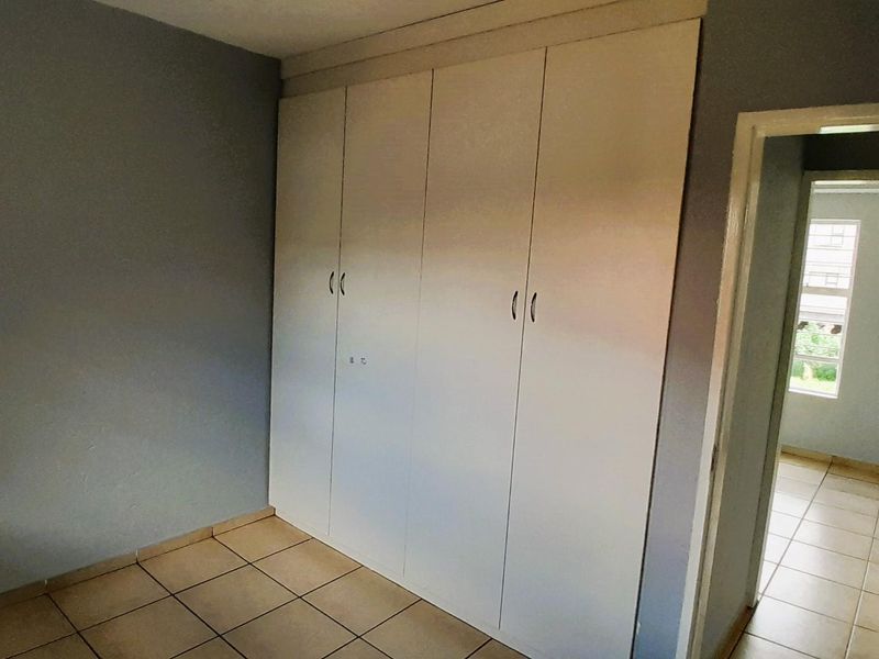 A clean, empty bedroom featuring built-in cupboards and tiled flooring, offering a neutral space ready for personalization.
