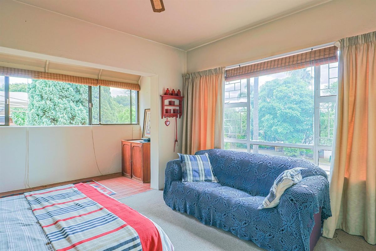A bedroom featuring large windows with natural light, carpeted flooring, and a connected alcove area with tiled flooring.