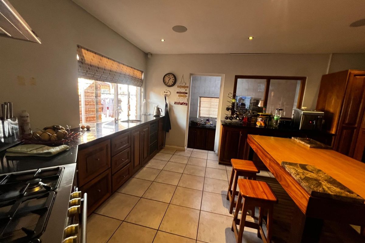 Spacious kitchen featuring dark wood cabinetry, granite countertops, a gas stove, and a central wooden island with integrated seating.