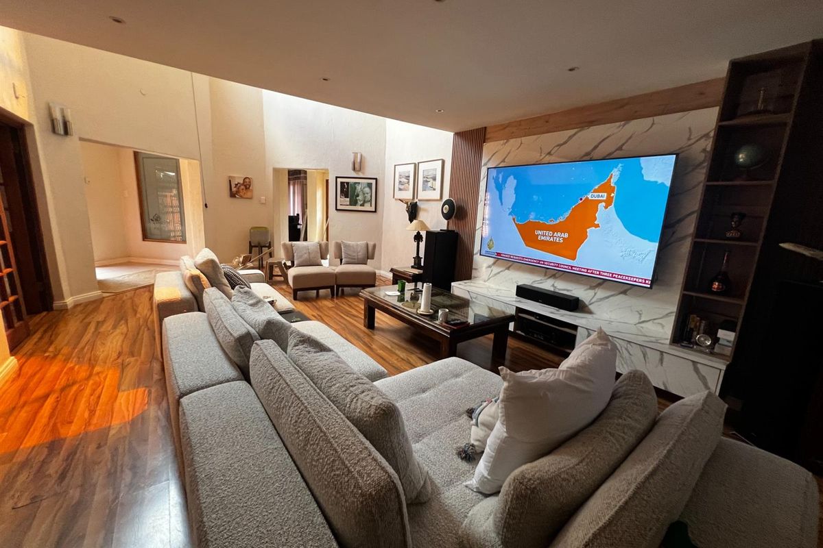 Spacious living room featuring high ceilings, hardwood flooring, and a modern marble-clad feature wall with integrated shelving and media setup.