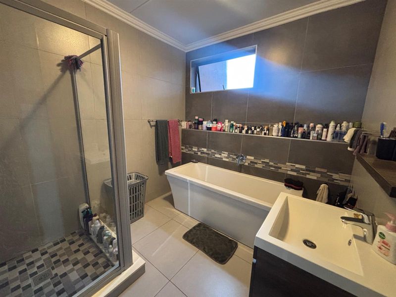 Modern bathroom featuring a glass shower enclosure, a freestanding bathtub, and a wall-mounted basin with contemporary tiled finishes and a built-in storage ledge.