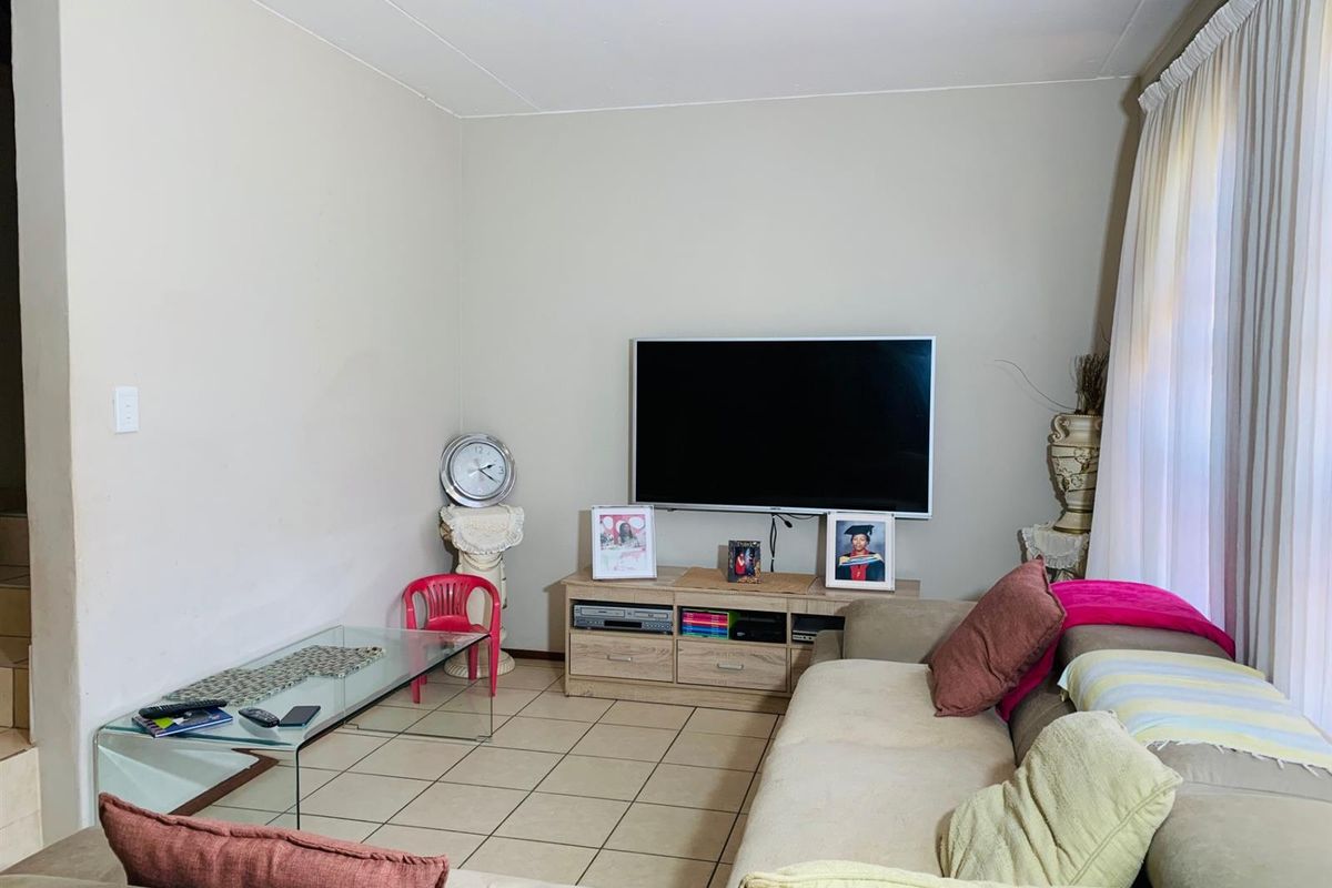A functional living room featuring neutral wall tones and tiled flooring, providing a comfortable space for relaxation and entertainment.