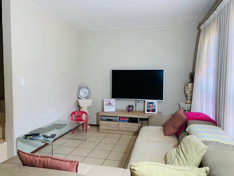 A functional living room featuring neutral wall tones and tiled flooring, providing a comfortable space for relaxation and entertainment.