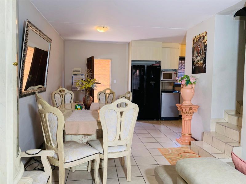 Open-plan dining and kitchen area featuring tiled flooring, built-in cabinetry, and direct access to the staircase.