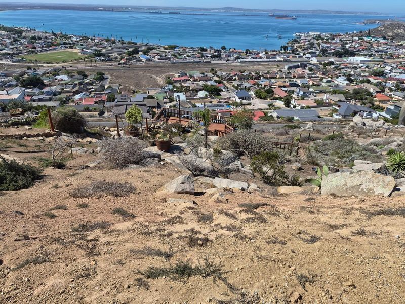Elevated view overlooking the coastal town, bay, and surrounding landscape from the vacant residential property.