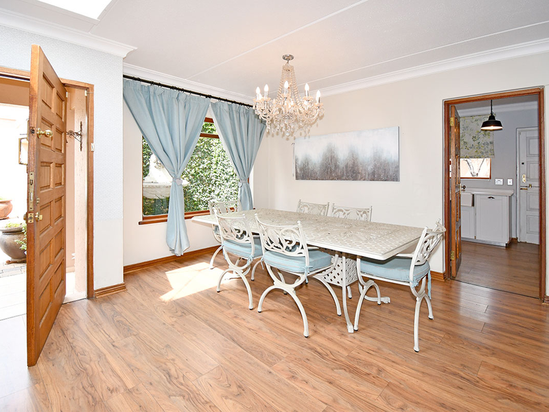 A bright dining room featuring laminate flooring, a crystal chandelier, and direct access to an outdoor patio area.