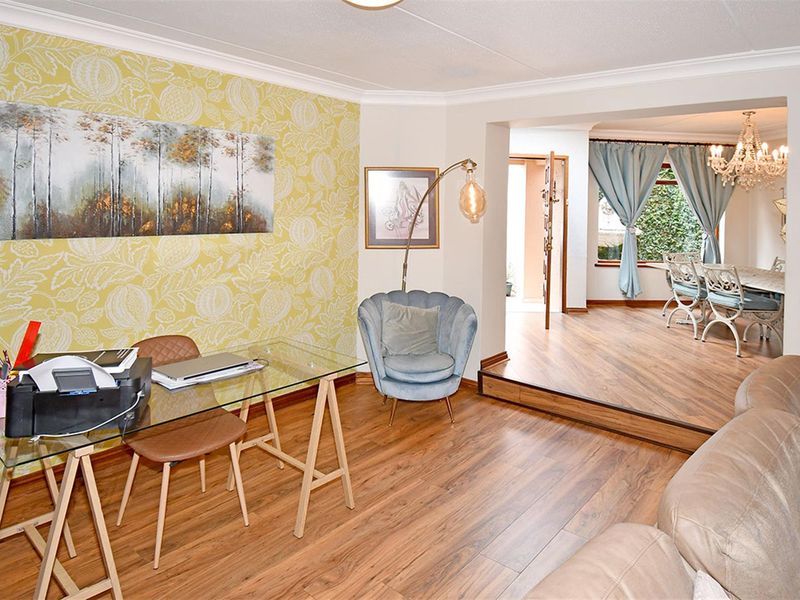 Open plan living area featuring laminate flooring, a raised dining section, and a decorative wallpapered feature wall.
