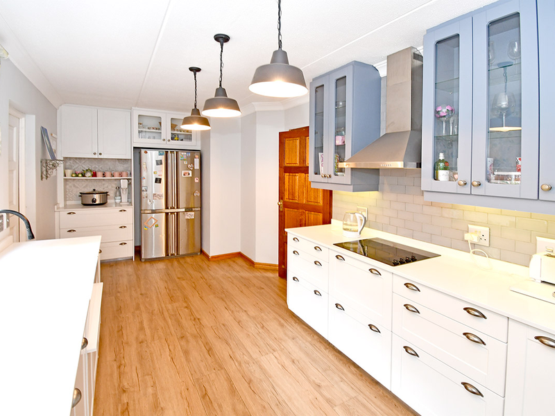 Modern kitchen featuring white and blue cabinetry, quartz countertops, subway tile backsplash, integrated appliances, and stylish pendant lighting over the workspace.