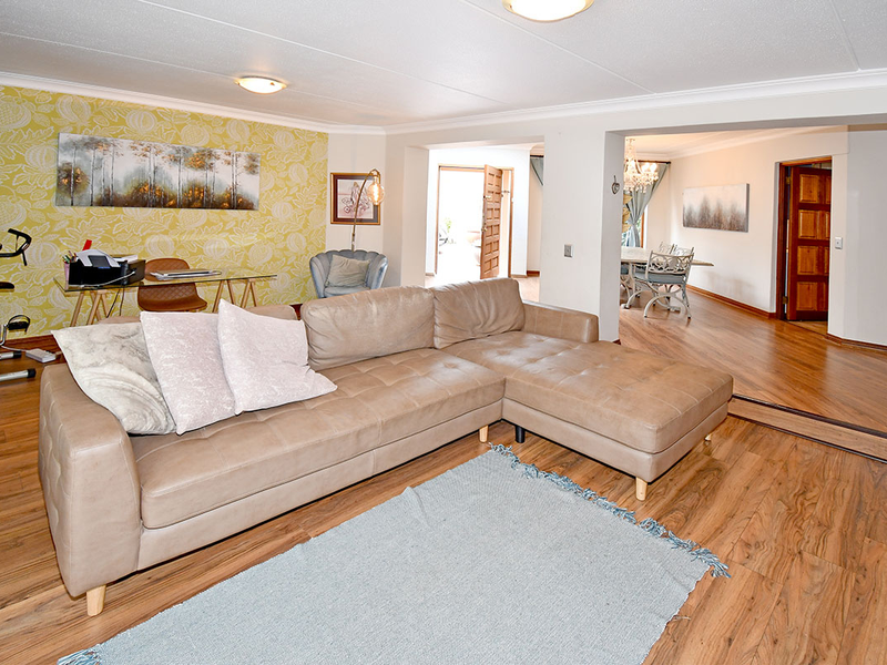 Spacious open-plan living area featuring laminate flooring, coved ceilings, and a seamless transition into the adjacent dining space.