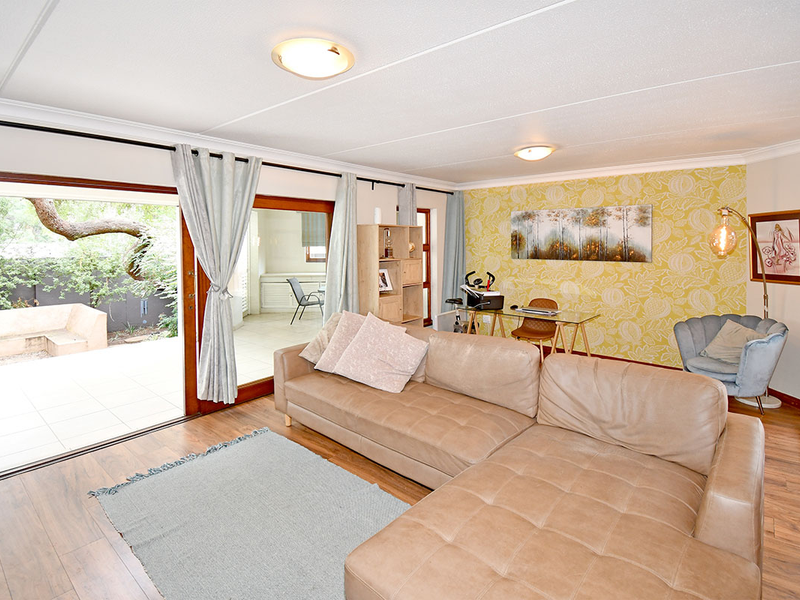 Spacious living room featuring laminate flooring, patterned accent wall, and large sliding glass doors providing seamless access to the outdoor patio area.