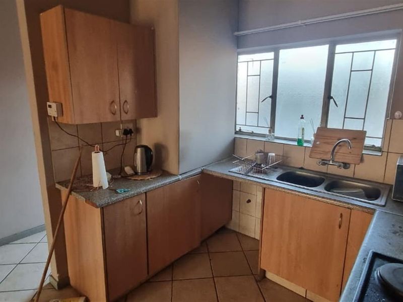A functional kitchen featuring laminate cabinetry, a double bowl stainless steel sink, tiled splashback, and built-in hob, offering a practical layout for daily use.