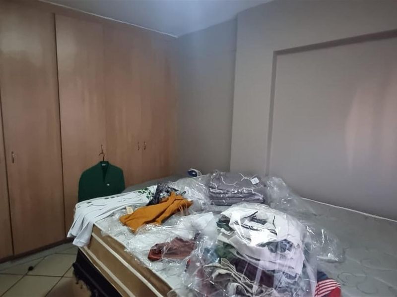 A bedroom featuring built-in wooden cupboards and tiled flooring, offering a functional space ready for personalization.