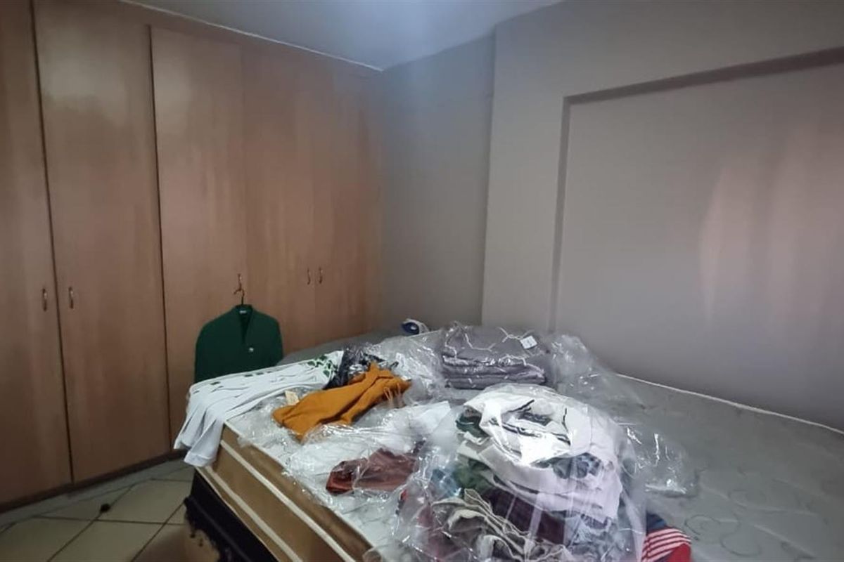 A bedroom featuring built-in wooden cupboards and tiled flooring, offering a functional space ready for personalization.