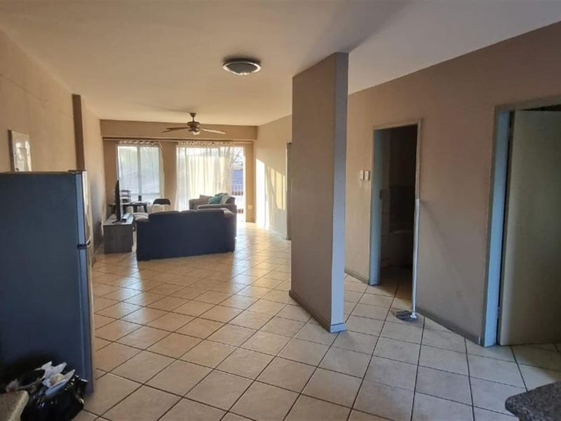 Open plan living area featuring tiled flooring, a ceiling fan, and neutral wall tones, providing a functional and connected space.