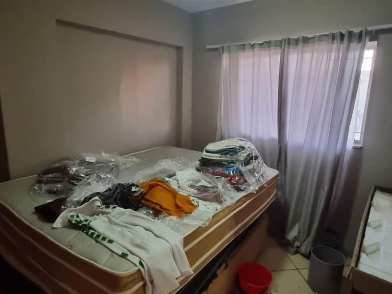 A bedroom featuring tiled flooring and a window with a curtain rod, providing a functional space for rest.